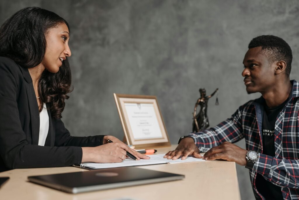 pexels-photo-8111887-8111887 Two adults engaging in a professional conversation at an office desk, showcasing collaboration.