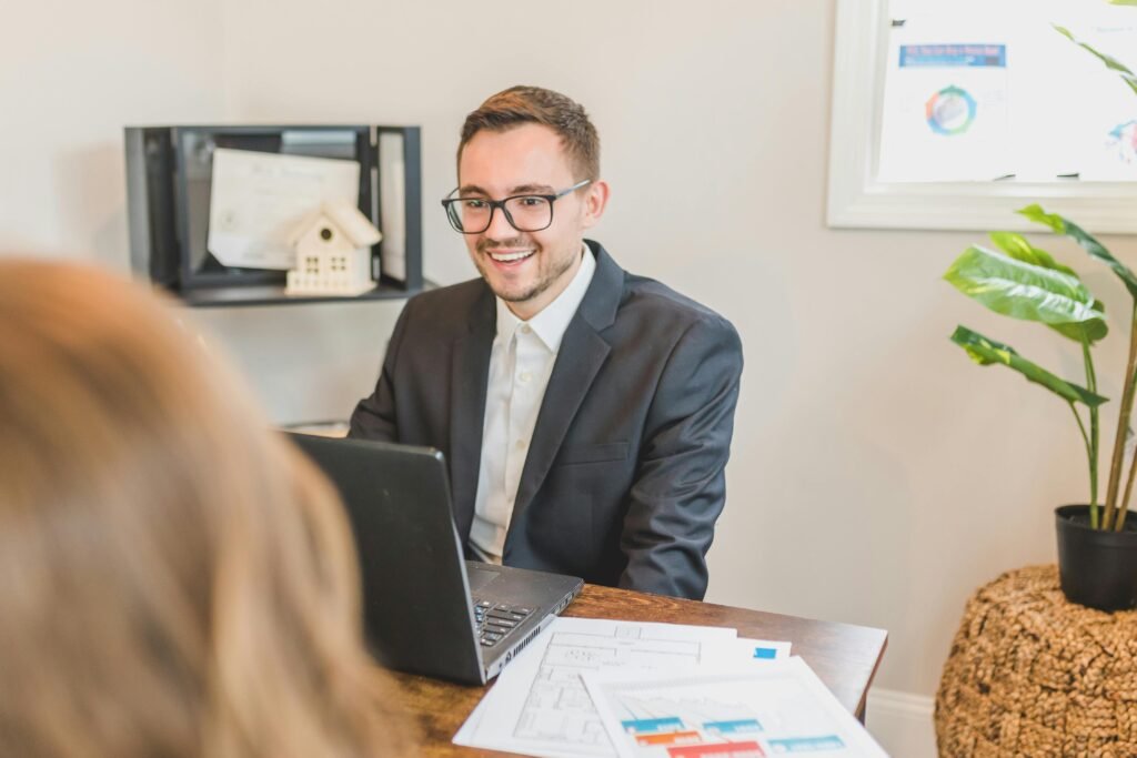 pexels-photo-8292849-8292849 A smiling businessman works at his desk with a laptop and documents in a modern office.